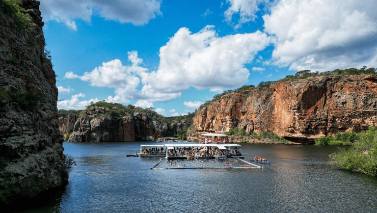 Catamarã navegando entre os paredões dos Cânions do Rio São Francisco, sob céu azul